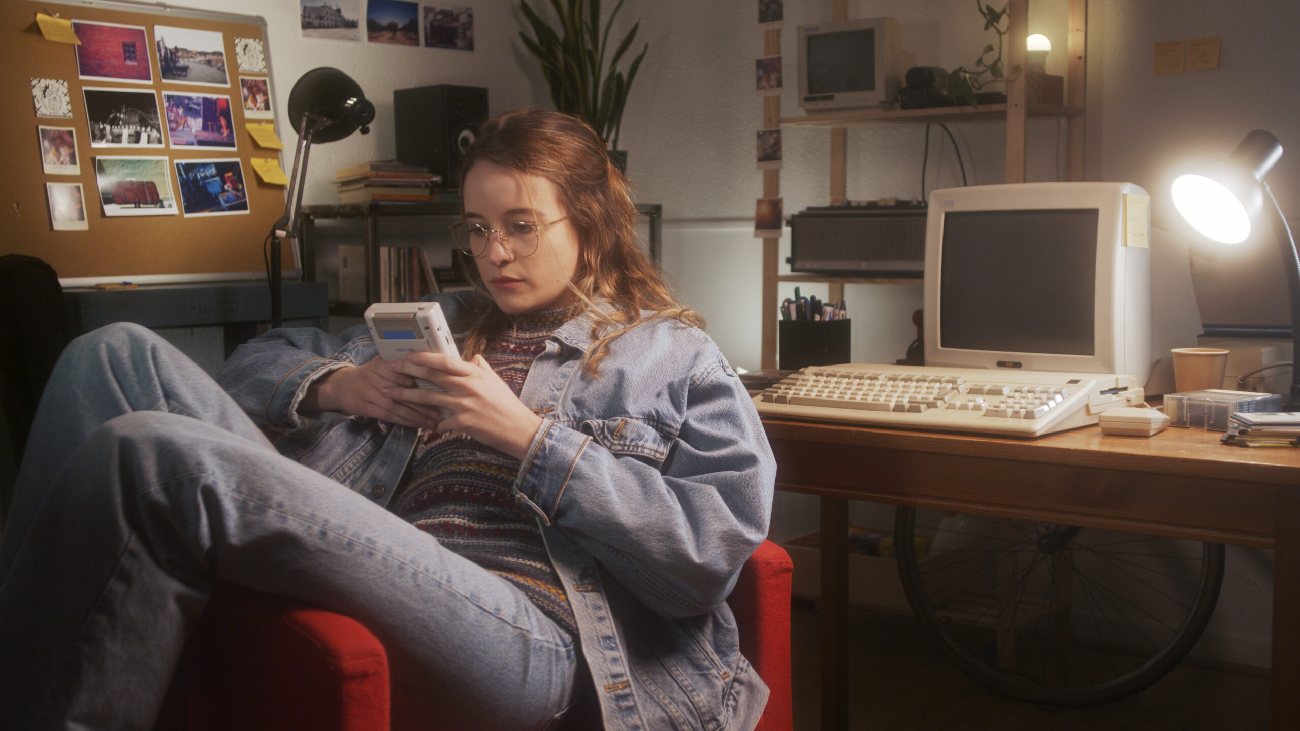 Teenager in the 1990s playing a gameboy in her room at her desk.