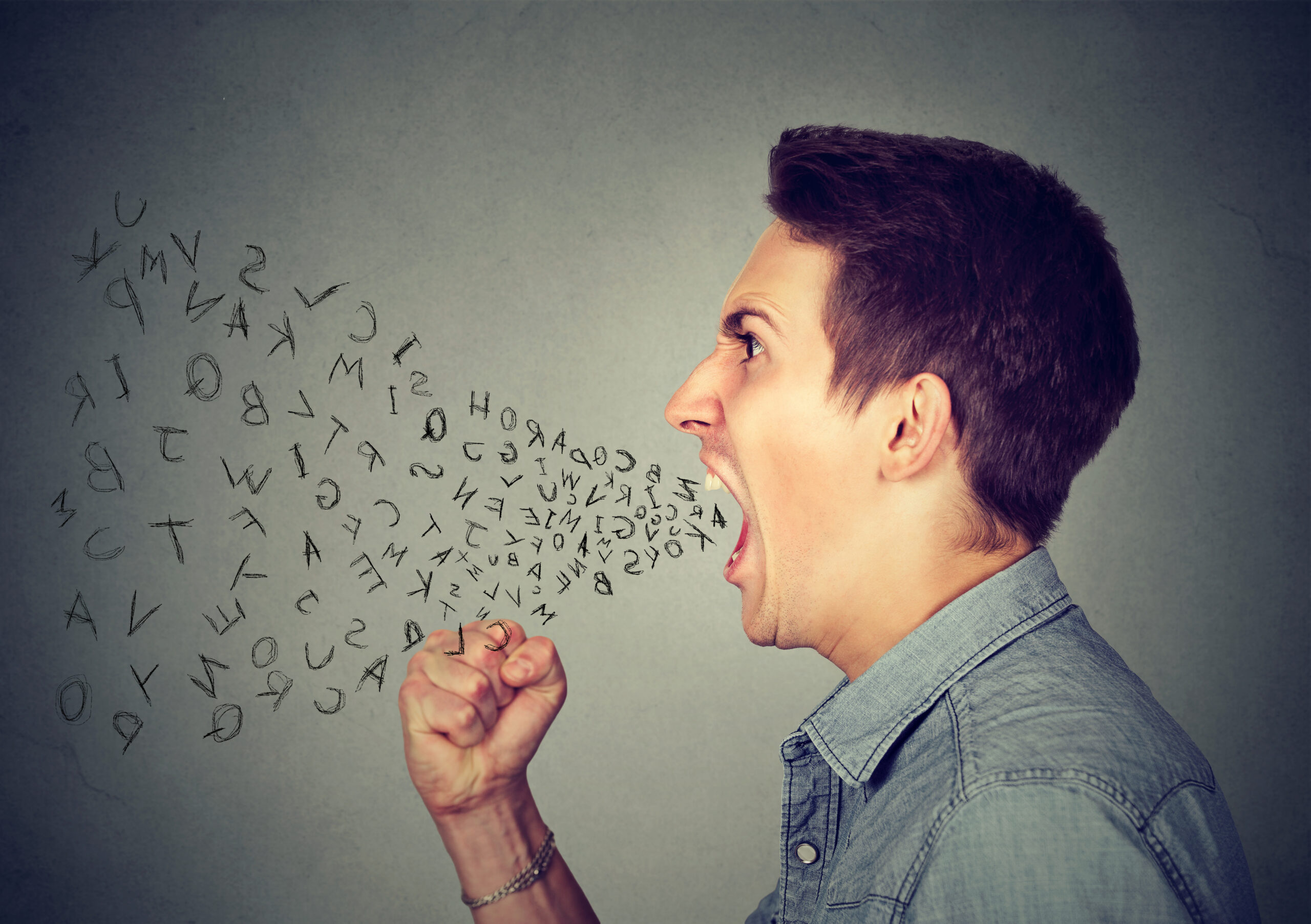 Side profile portrait of young angry man shouting slang insults